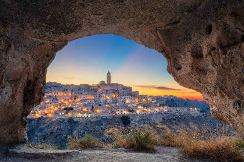 view of Sassi di Matera UNESCO site from a grotto cave at sunset